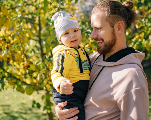 Man walking outside holding toddler