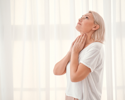 Woman feeling her thyroid area 